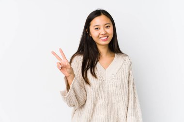Young chinese woman isolated joyful and carefree showing a peace symbol with fingers.