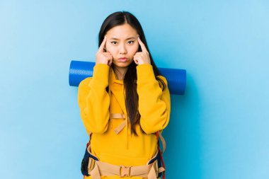 Young chinese backpacker woman isolated focused on a task, keeping forefingers pointing head.