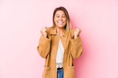 Kafkasyalı genç bir kadın münzevi poz veriyor yumruğunu kaldırıyor, mutlu ve başarılı hissediyor. Zafer konsepti.