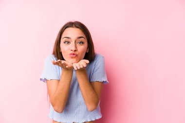 Kayak kıyafetleri giyen genç beyaz bir kadın. Dudaklarını katlıyor ve hava öpücüğü yollamak için avuç içi tutuyor..