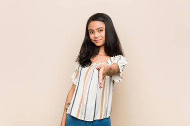 Genç, sevimli Çinli genç, sarışın kadın pembe arka planda ceket giyiyor. Kameraya elini uzatıp selam veriyor..