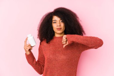 Vitaminlerini tutan genç afro bir kadın vitaminlerini tutan, hoşlanmadığı bir jesti gösteren genç bir afro kadın, kabul etmiyor. Anlaşmazlık konsepti.