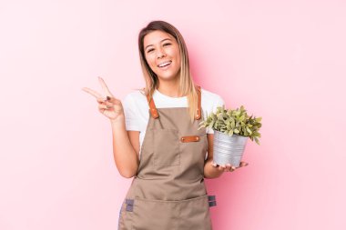 Genç bahçıvan Kafkasyalı kadın neşeli ve kaygısız bir şekilde parmaklarıyla barış sembolü gösteriyor..