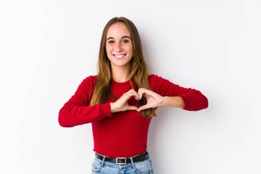Kafkasyalı genç bir kadın yalnız poz veriyor gülümsüyor ve elleriyle kalp şeklini gösteriyor..