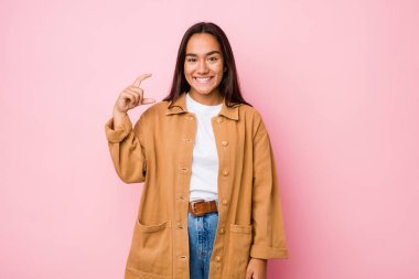 Genç melez Hintli kadın kendini izole edip işaret parmağıyla küçük bir şey tutuyor, gülümsüyor ve kendinden emin..