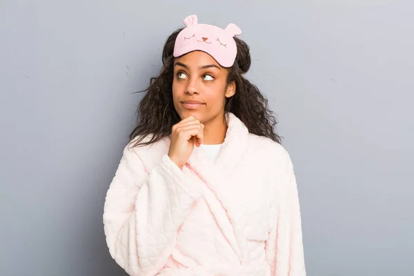 身穿睡衣和睡眠面具的年轻的非洲裔美国女人带着怀疑和怀疑的表情侧视着 — 图库照片
