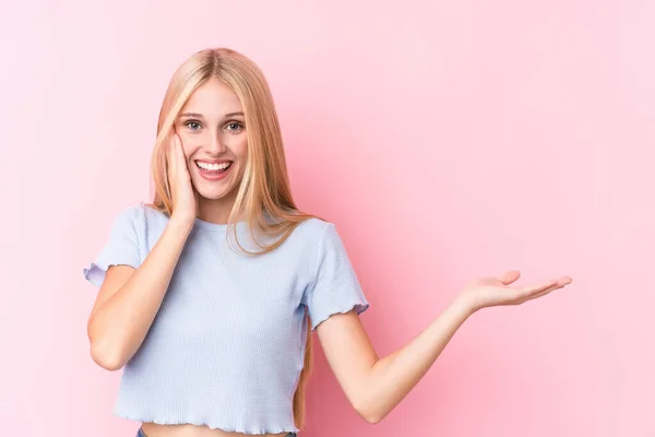 Jonge Blonde Vrouw Roze Achtergrond Houdt Kopieerruimte Een Handpalm Houd — Stockfoto