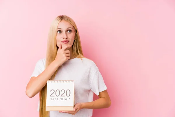 Menina Segurando Calendário 2020 Olhando Para Lados Com Expressão Duvidosa — Fotografia de Stock