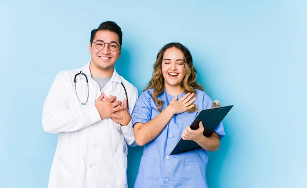 Mavi Arka Planda Poz Veren Genç Doktor Çift Gülüyor Ellerini — Stok fotoğraf