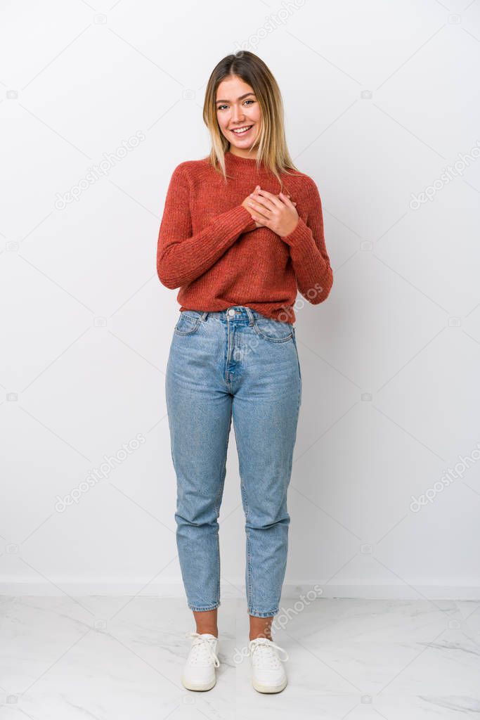 Full body young caucasian woman has friendly expression, pressing palm to chest. Love concept.