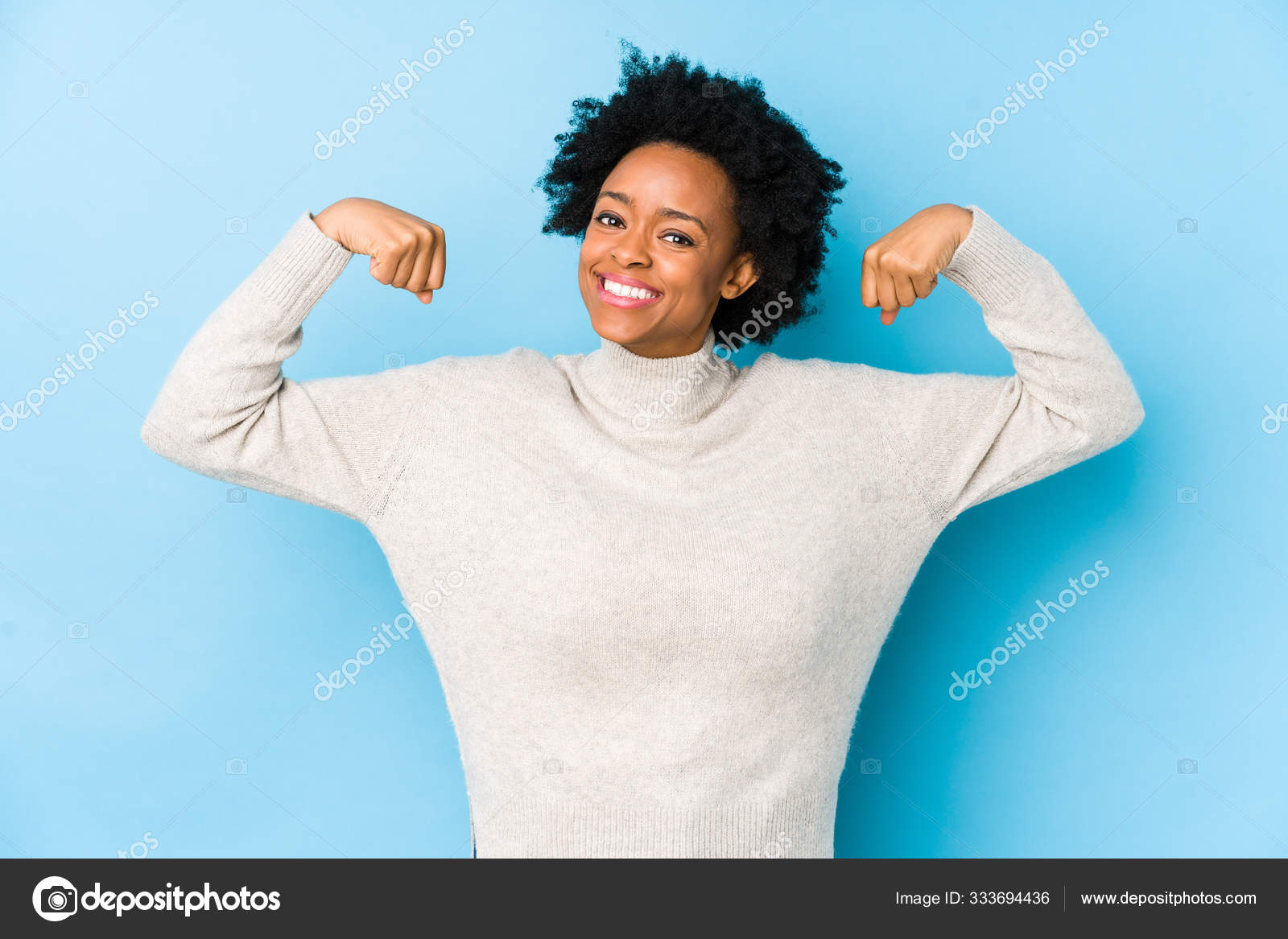 女性の力の象徴である腕を持つ強さのジェスチャーを示す青の背景に孤立した中高年アフリカ系アメリカ人女性 ストック写真 C Asierromerocarballo