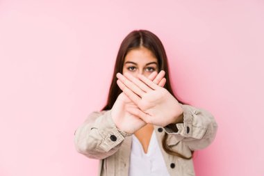 Young caucasian woman posing in a pink background doing a denial gesture