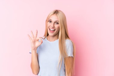 Pembe arka plandaki genç sarışın kadın göz kırptı ve elleriyle iyi bir jest yaptı..