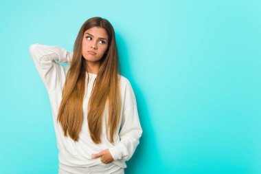 Young slim woman touching back of head, thinking and making a choice.