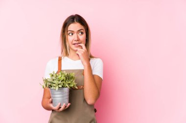 Pembe arka planda genç beyaz bahçıvan kadın rahatlamış fotokopi odasına bakan bir şey düşünüyor..