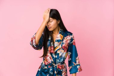 Kimono pijamalı genç Asyalı kadın bir şey unutmuş, alnına avuç içi ve gözlerini kapatmış..