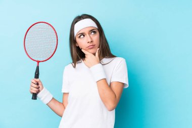 Badminton oynayan beyaz bir kadın şüpheli ve şüpheci bir ifadeyle yanlamasına bakıyor..