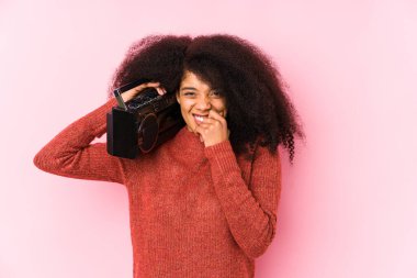 Young afro woman holding a cassete isolated biting fingernails, nervous and very anxious.