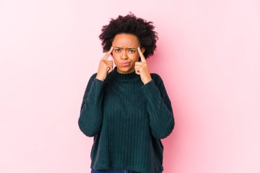 Orta yaşlı Afro-Amerikalı bir kadın pembe bir geçmişi var. Bir göreve odaklanmış vaziyette. İşaret parmaklarını işaret ediyor..
