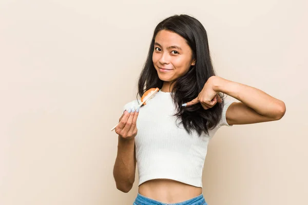 Młoda Azjatycka Kobieta Trzyma Sushi Kawałek Zaskoczony Wskazując Siebie Uśmiechnięty — Zdjęcie stockowe