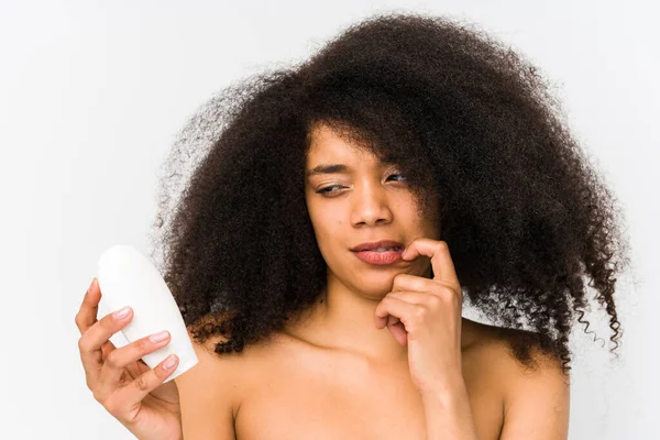 Mujer Afro Joven Sosteniendo Una Crema Hidratante Aislado Relajado Pensando — Foto de Stock