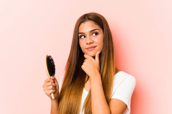 Młoda Kaukaska Kobieta Trzyma Szczotkę Włosów Patrząc Bokiem Wątpliwą Sceptyczną — Zdjęcie stockowe