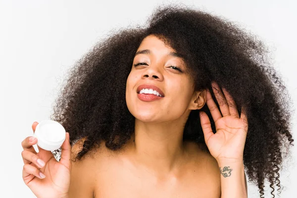 Joven Afro Mujer Sosteniendo Una Crema Hidratante Aislado Tratando Escuchar — Foto de Stock