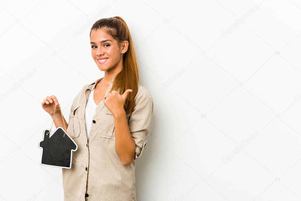 Young caucasian woman holding a house icon smiling and raising thumb up
