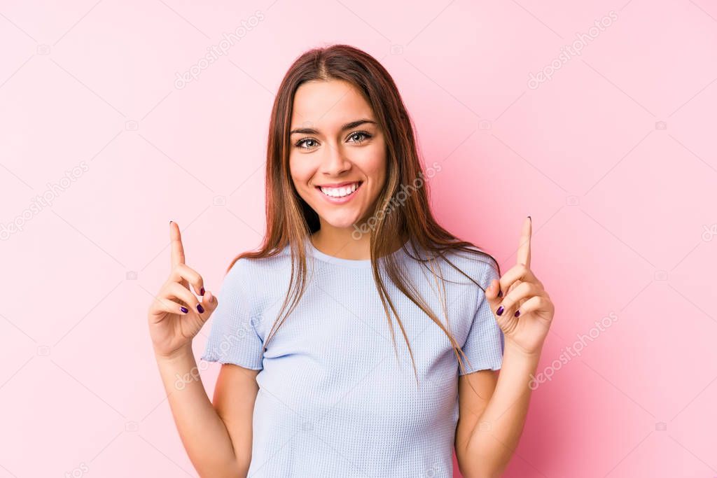 Young caucasian woman wearing a ski clothes isolated indicates with both fore fingers up showing a blank space.