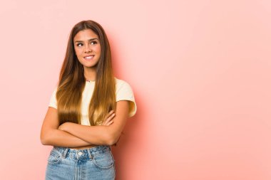 Kollarını kavuşturarak gülümseyen zayıf genç bir kadın..