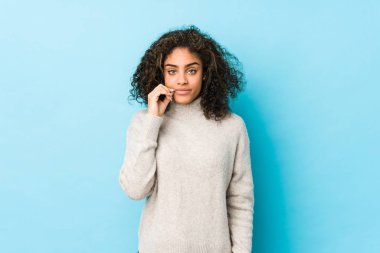 Genç Afro-Amerikan kıvırcık saçlı, parmakları dudaklarında bir sır saklayan kadın..