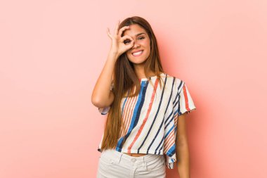 Young slim woman excited keeping ok gesture on eye.