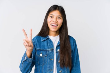 Genç Asyalı kadın zafer işareti gösteriyor ve gülümsüyor..