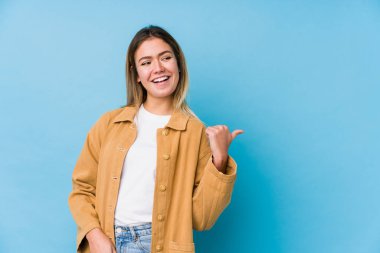 Genç beyaz kadın başparmağıyla işaret ediyor, gülüyor ve kaygısız..