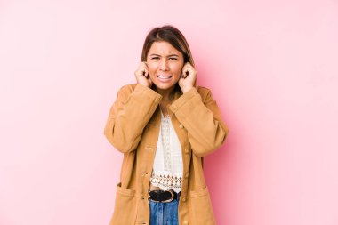 Kafkasyalı genç bir kadın yalnız poz verip kulaklarını elleriyle kapatıyor..