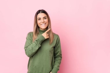 Kafkasyalı genç bir kadın kendini izole edip gülümsüyor ve boş alanda bir şeyler gösteriyor..