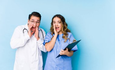 Mavi arka planda poz veren genç doktor çiftin bağırışları ön plana çıkıyor..