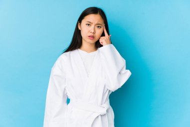 Karate yapan genç Çinli kadın işaret parmağıyla hayal kırıklığı işareti yapıyor..