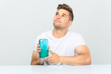 Elinde gargara tutan genç adam şüpheli ve şüpheci bir ifadeyle yana bakıyor..