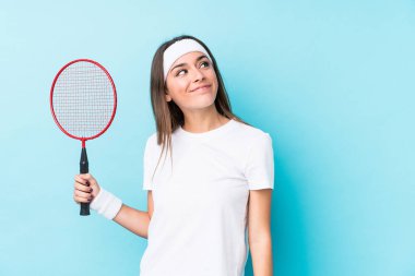 Badminton oynayan beyaz bir kadın hedeflerine ve amaçlarına ulaşma hayali kuruyor.