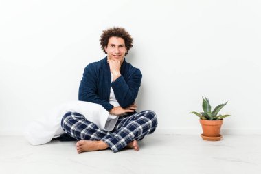 Mutlu ve kendinden emin gülümsüyor, elleriyle çeneye dokunuyor..