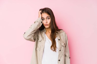 Young caucasian woman posing in a pink background tired and very sleepy keeping hand on head.