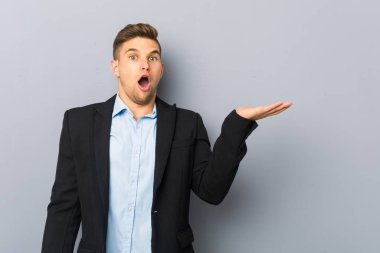 Genç, yakışıklı, beyaz bir adam, avuç içi fotokopi alanını elinde tutmaktan etkilenmiş..