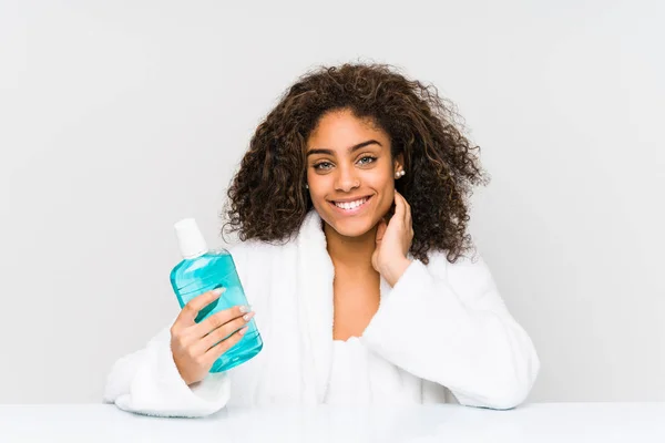 Young african american woman holding a mouth wash happy, smiling and cheerful.