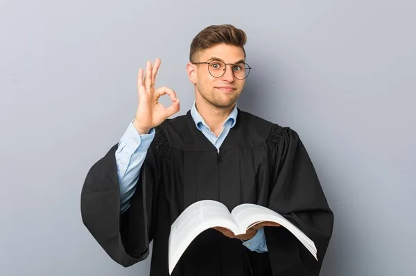 Young Jurist Holding Book Cheerful Confident Showing Gesture — Stock Photo, Image