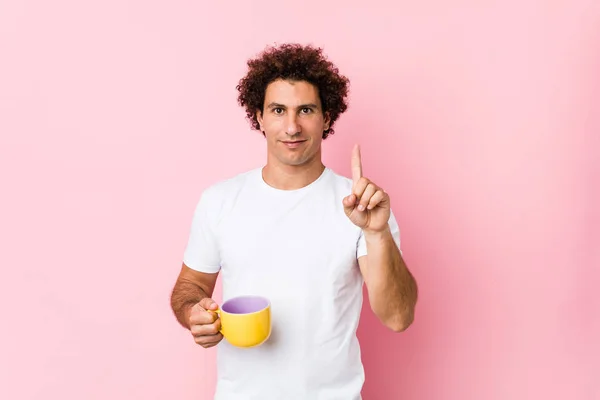 Joven Hombre Rizado Caucásico Sosteniendo Una Taza Mostrando Número Uno — Foto de Stock