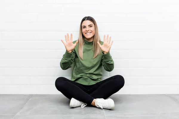 Jovem Caucasiana Sentada Chão Mostrando Número Dez Com Mãos — Fotografia de Stock