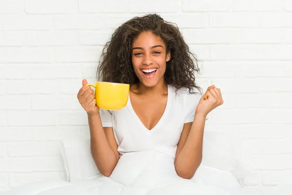 Jovem Afro Americana Sentada Cama Segurando Uma Caneca Café Torcendo — Fotografia de Stock