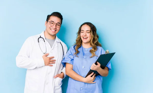 Joven Pareja Médicos Posando Fondo Azul Aislado Ríe Voz Alta —  Fotos de Stock