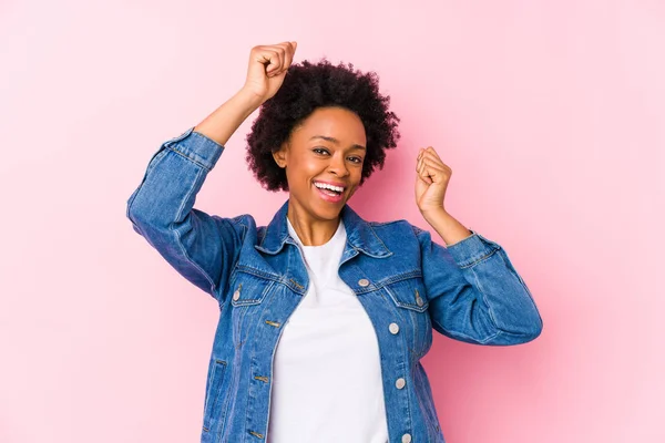 年轻的非洲裔美国女人面对着粉红的背脊孤立地庆祝着一个特殊的日子 勇敢地跳起来 举起双臂 — 图库照片